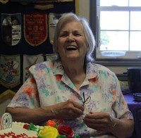 Smiling elderly woman celebrating birthday with cake.