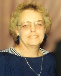 Smiling person wearing glasses and a blue outfit.