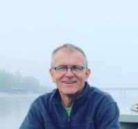 Smiling man in a foggy outdoor setting.