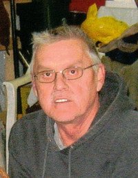 Older man with glasses and gray hair smiling.