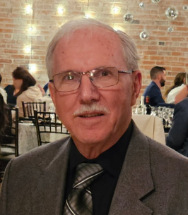 Elderly man in suit at formal event with guests.