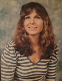 Smiling woman with curly hair and striped shirt.
