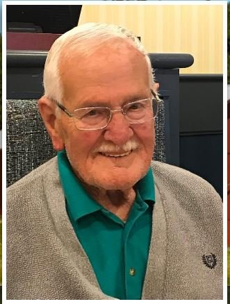 Smiling elderly man with glasses and sweater.