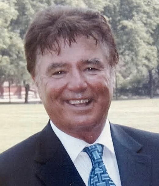 Smiling man in suit and tie outdoors.