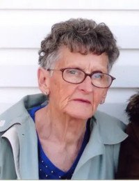 Elderly woman with glasses and short hair.