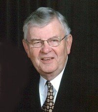 Elderly man in suit and glasses smiling