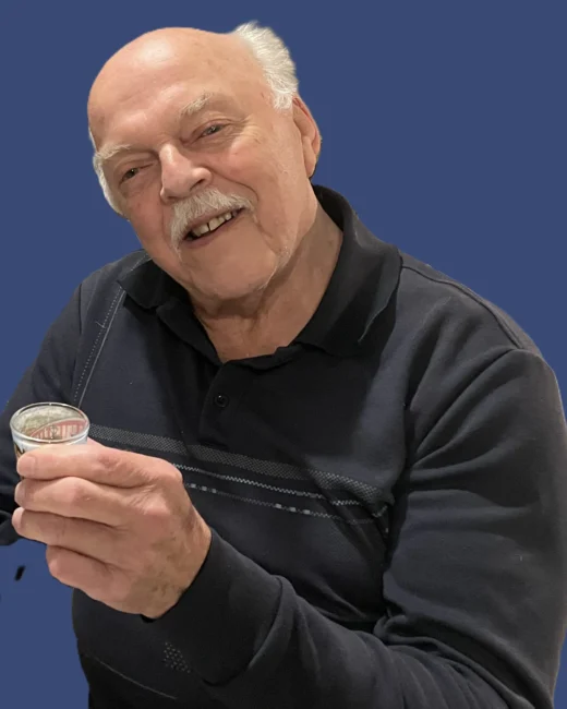 Smiling man holding a small cup.