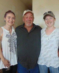 Three smiling people standing together indoors.