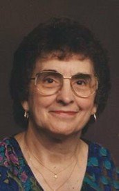 Elderly woman wearing glasses and smiling.