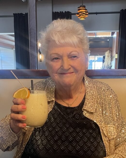 Woman enjoying a fruity cocktail at a restaurant.