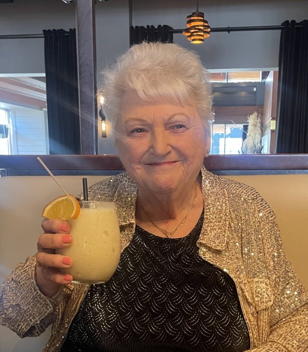 Woman enjoying a fruity cocktail at a restaurant.