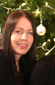 Woman smiling by Christmas tree decorations