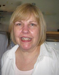 Smiling woman with short blonde hair indoors.