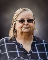 Woman wearing glasses and plaid shirt, neutral background.