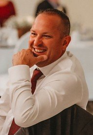 Smiling man in white shirt and red tie.