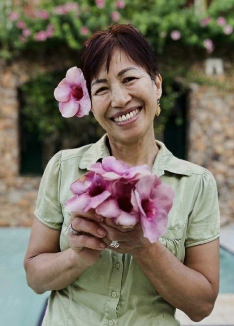 Smiling woman holding pink flowers outdoors.