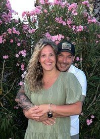 Couple smiling in front of blooming pink flowers.