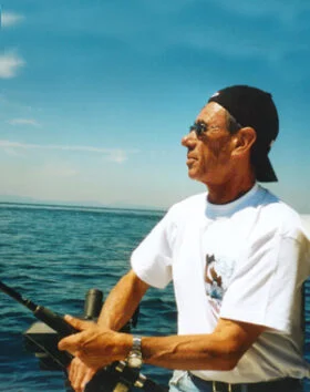 Man fishing on a boat in open ocean.