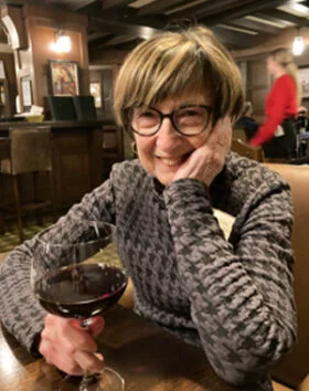 Woman smiling with wine glass in a restaurant.