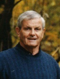 Smiling man in a blue sweater outdoors.
