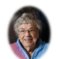 Smiling elderly woman with glasses and curly hair.