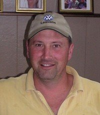 Smiling man wearing a VW cap indoors.