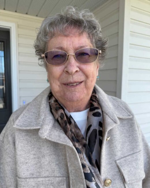 Elderly woman smiling outside a house