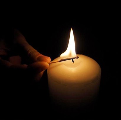 Lit candle with a match in the dark
