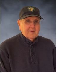 Elderly man in sweater and hat, studio portrait.
