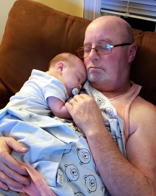 Man and baby sleeping on couch with blanket