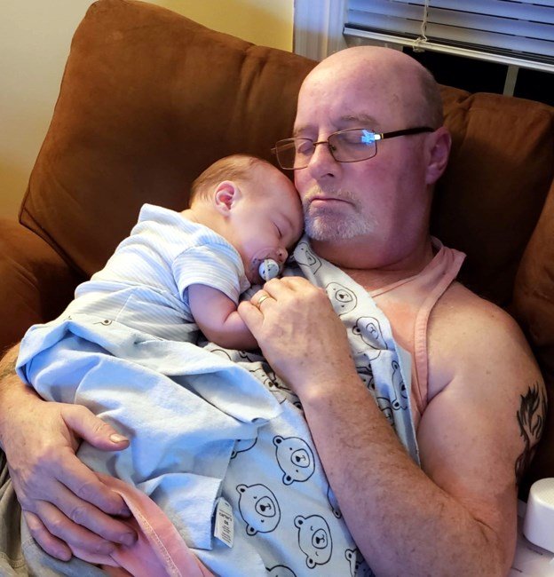 Man and baby sleeping on couch with blanket