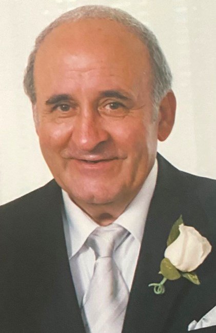 Smiling person in suit with white rose boutonniere.