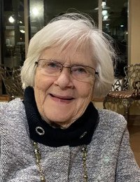 Smiling elderly woman with white hair indoors.