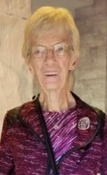 Elderly person smiling in a maroon jacket.