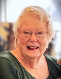Smiling elderly person with glasses and short hair.