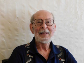 Smiling elderly man wearing glasses indoors.