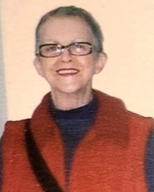 Smiling person in glasses and red vest.