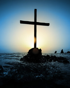 Silhouette of cross against sunset over water
