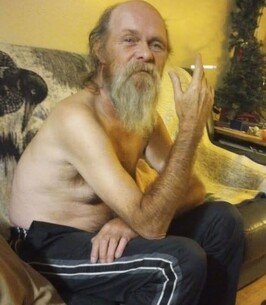 Elderly man sitting on a couch at home.
