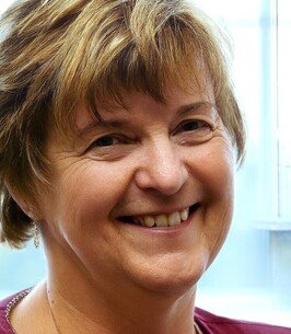 Smiling woman near window with short hair.