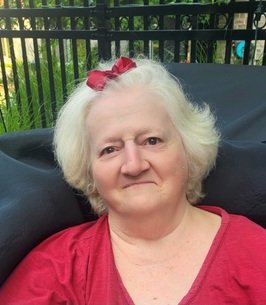 Smiling woman with white hair in red shirt.
