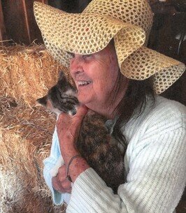 Smiling woman in hat holding a cat.