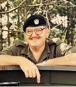 Smiling man in military uniform outdoors.