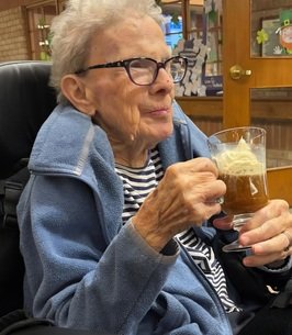 Elderly woman enjoying a root beer float.