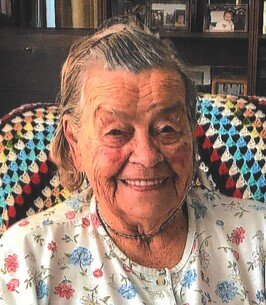 Smiling elderly woman sitting in a cozy chair.