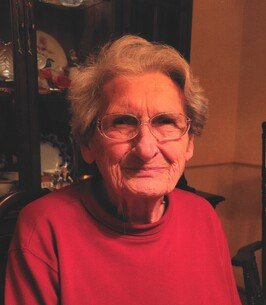 Smiling elderly woman wearing glasses indoors.