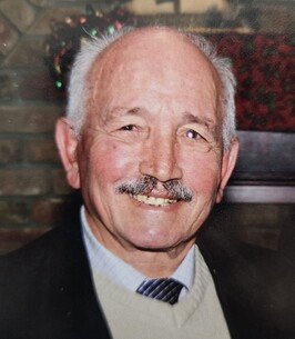 Smiling elderly man with white hair and mustache.