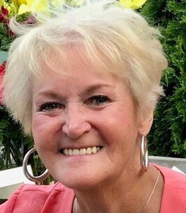 MCLEAN, Jean McLean Smiling person with short blonde hair and hoop earrings
