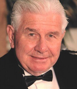 Elderly man in tuxedo smiling at camera.