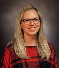 Smiling woman with glasses and red plaid shirt.